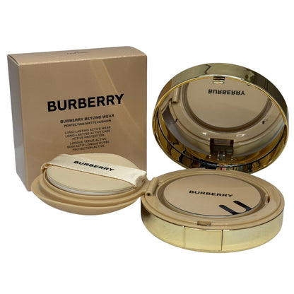 Burberry Beyond Wear Perfecting Matte Cushion foundation shown with its gold-toned outer box, open compact, and closed compact on a white background.