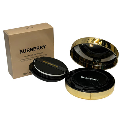 Burberry Ultimate Glow Cushion compact shown open next to its beige packaging box on a white background.