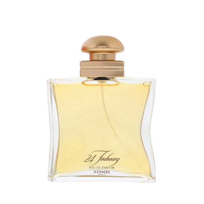 Hermes 24 Foubourg Eau de Parfum bottle with a curved clear glass body, pale yellow liquid, and a metallic gold cap, shown on a white background.