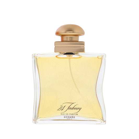 Hermes 24 Foubourg Eau de Parfum bottle with a curved clear glass body, pale yellow liquid, and a metallic gold cap, shown on a white background.