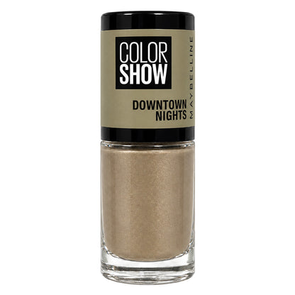 Maybelline Color Show Downtown Nights nail polish in a clear glass bottle with a black cap and a beige label, showing a shimmering champagne-gold liquid inside.