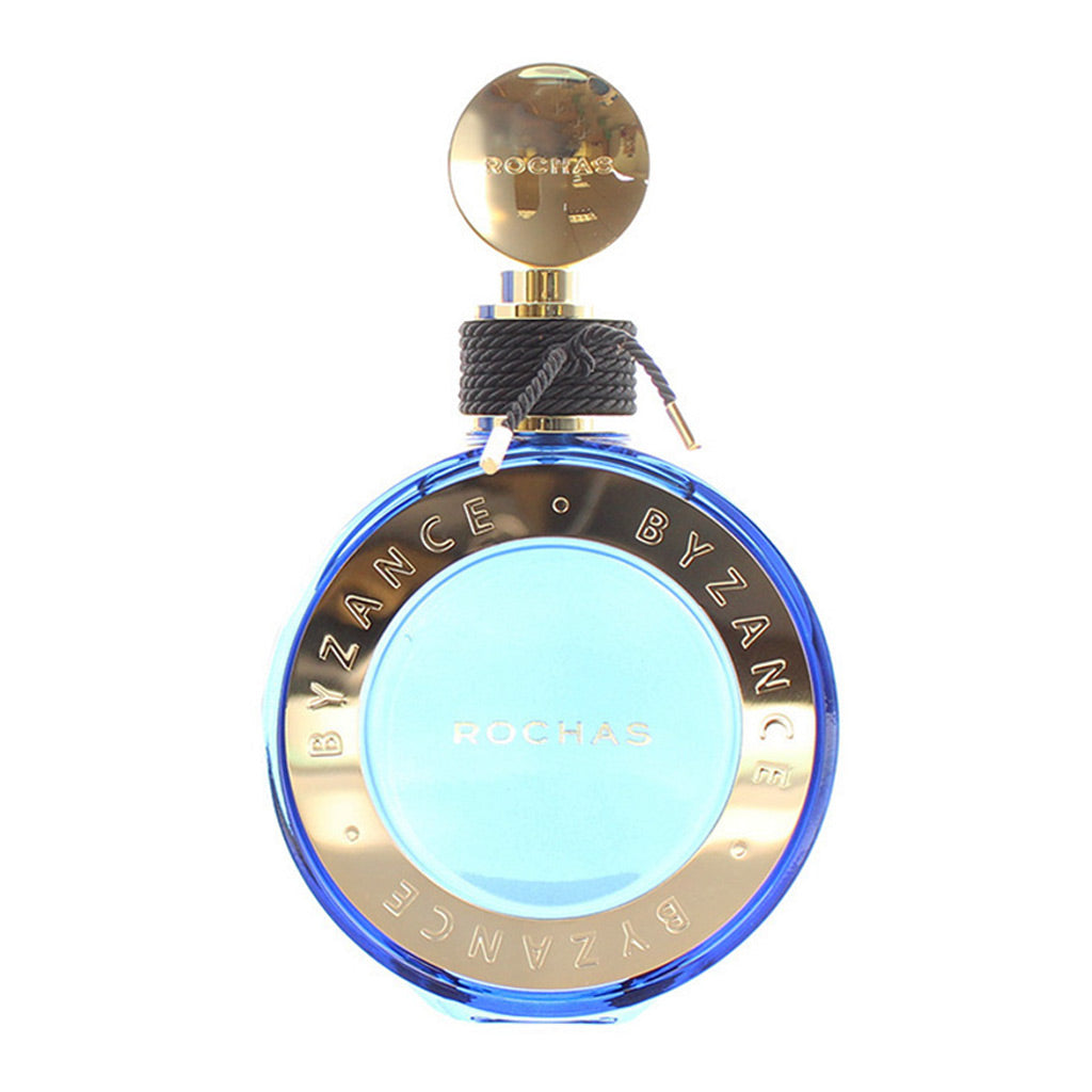 Rochas Byzance perfume bottle, featuring a round blue glass body with a gold-toned metallic band, a light blue center, and a gold cap with a black rope detail, set against a plain white background.