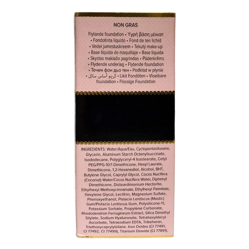 A rectangular foundation stick package shown upright on a white background. The top portion is a dusty pink panel with product name and text, the center is a black band, and the bottom portion is a light pink panel with ingredients listed in small print.