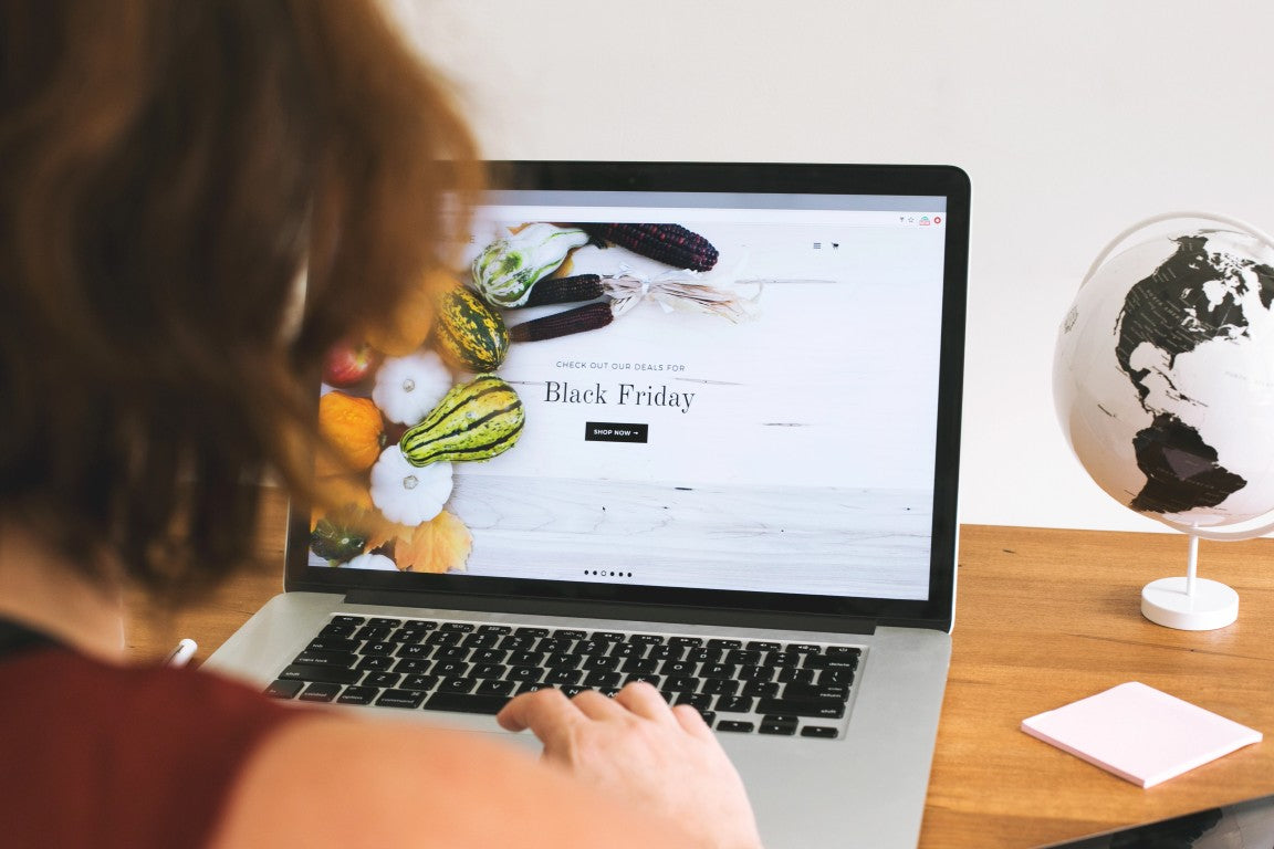 Person using a laptop with a Black Friday website on a desk with a world map in the background